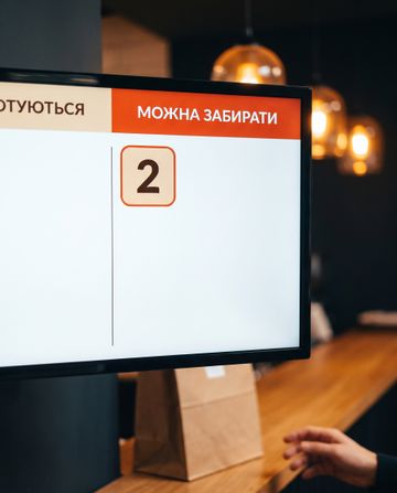 Гість забирає готове замовлення під підсвіченим номером на екрані видачі